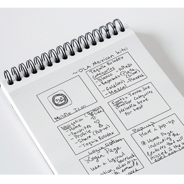 Image of a sketchbook with my drawings in black pen of logo ideas and other sketches