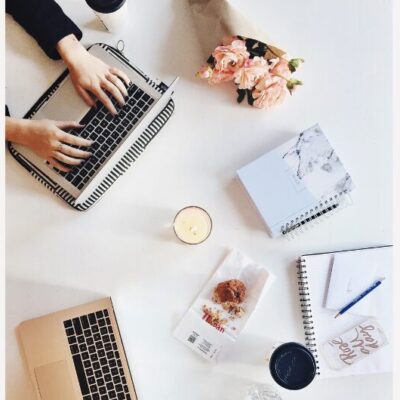 Image of a person working at a computer, birds eye view of their desk with drinks